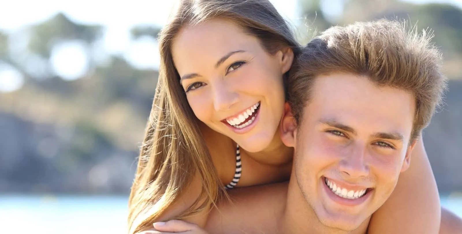 Jeune couple souriant à l'extérieur par une journée ensoleillée